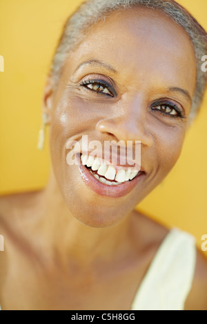 portrait of african 50 years old surprised woman with white hair, smiling on yellow background Stock Photo