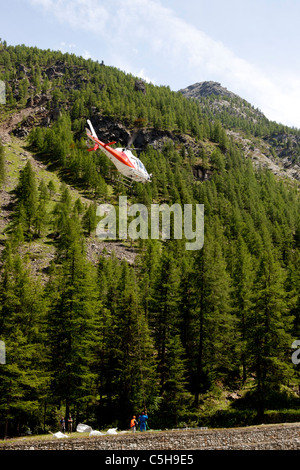 A lift operation by a helicopter in a moutainous site (Aosta valley - Italy).  Opération de levage en montagne par hélicoptère. Stock Photo