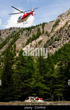 A lift operation by a helicopter in a moutainous site (Aosta valley - Italy).  Opération de levage en montagne par hélicoptère. Stock Photo