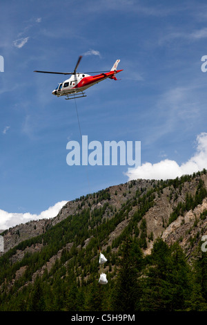 A lift operation by a helicopter in a moutainous site (Aosta valley - Italy).  Opération de levage en montagne par hélicoptère. Stock Photo