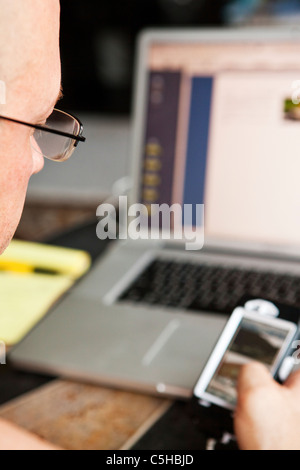 Man using iphone and laptop computer Stock Photo