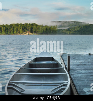 canoe by dock on Adirondack lake at sunrise Stock Photo