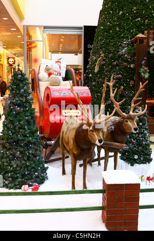 Christmas doll at Christmas fair in a shopping mall, two Santa's reindeer with his sledge Stock Photo