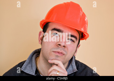 A young construction working with a pensive or contemplative look thinking hard about something. Stock Photo