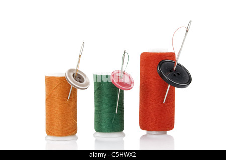 three colored spool with needles and buttons Stock Photo