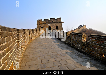 The Great Wall of China with two watchtowers visible as the wall climbs a rise in golden late afternoon light, at Mutianyu Stock Photo