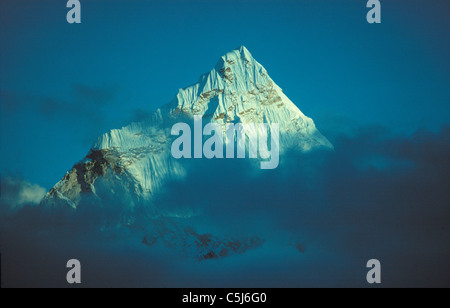 The summit of Ama Dablam rises above evening clouds in the Everest valley, Khumbu region, Nepal Himalaya Stock Photo