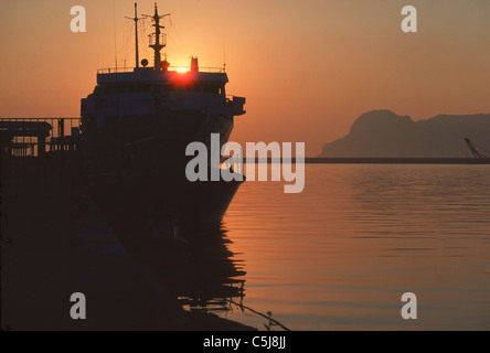 Dawn in the port of Algeciras with shipping silhouetted against the rising sun and distant views of Gibraltar Rock Stock Photo