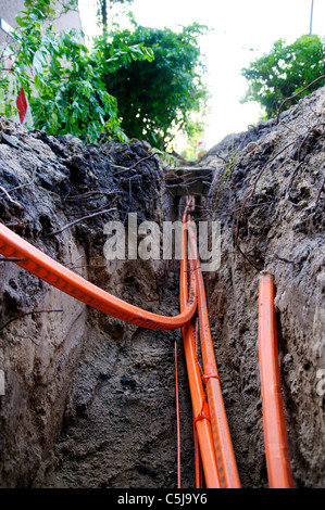 Orange fiberglass cables in a trench in a Dutch city, connecting private homes to high speed broadband internet. Stock Photo