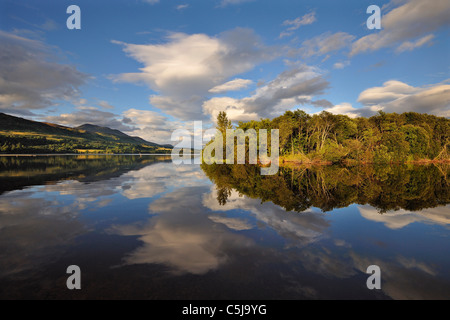 Dramatic evening light on distant hills and islands reflected in still water at Loch Tay, Perthshire, Scotland, UK Stock Photo