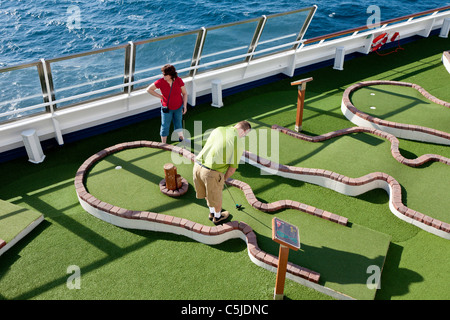 Cruise passengers playing miniature golf on the deck of Carnival's Triumph cruise ship in the Gulf of Mexico Stock Photo