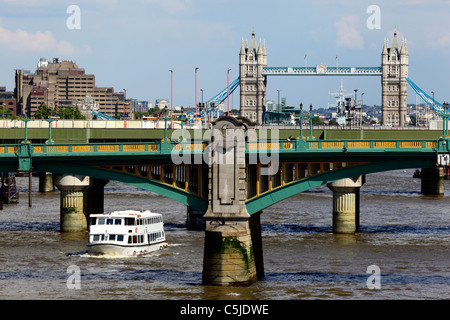 View along River Thames to Tower Bridge, cruise boat passing under Southwark Bridge in foreground, London, England Stock Photo