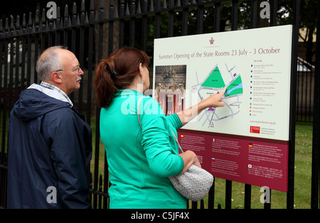 Tourists reading the summer opening times for the State Rooms at Buckingham Palace, London, England, U.K. Stock Photo
