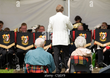 Elderly man and woman seated and watching a brass band playing in old Amersham Bucks UK. Stock Photo