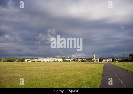 View of path across the heath to village suburb and All Saints Parish Church in the evening. Blackheath, London, England, UK, Britain. Stock Photo