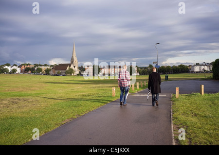 Two young men walking across the heath to the village. Blackheath, London, England, UK, Britain. Stock Photo