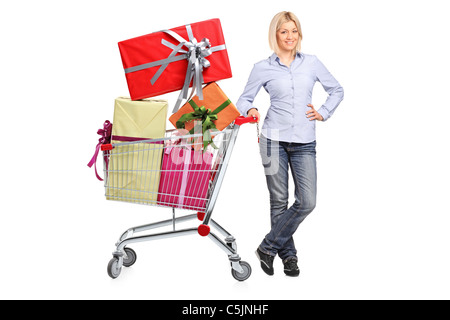 A woman posing next to a shopping cart full with gifts Stock Photo