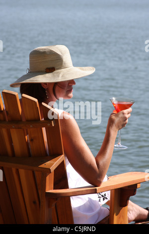 A lady drinking a cocktail next to a lake Stock Photo