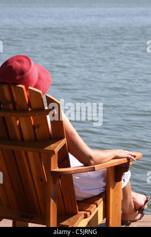 A lady drinking a cocktail next to a lake Stock Photo