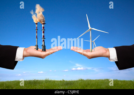 pollution and clean energy concept. businessman holding windmills and refinery with air pollution