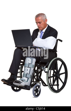 Photo of an injured businessman sitting in a wheelchair working on a laptop computer, isolated against a white background. Stock Photo