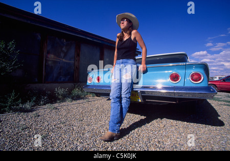 Young woman in torn blue jeans resting on a 'Chevrolet Belair' car, Cerillos, New Mexico, USA (MR) Stock Photo