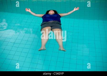 Woman floating in the water of a swimming pool Stock Photo