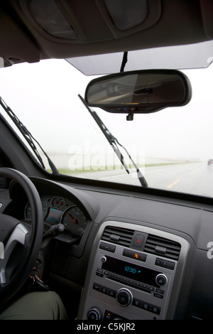 car driving on single highway through heavy rainstorm and flooding fields in southern saskatchewan canada Stock Photo