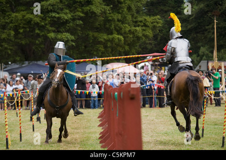 two knights in armour galloping on brown horses in a jousting tournament, one lance breaking, Upper Hutt, New Zealand Stock Photo