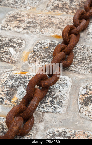 Large / big and rusting metal iron chain links on granite setts - Cornish fishing harbour. UK. Stock Photo