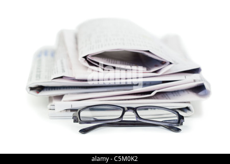 A pile of newspapers and a pair of reading glasses