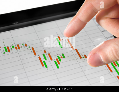 Touching stock market graph on a touch screen device. Stock Photo