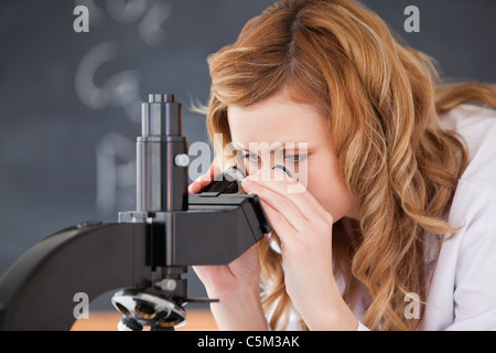 Blond-haired woman looking through a microscope Stock Photo