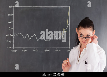 Dark-haired scientist standing near the blackboard Stock Photo