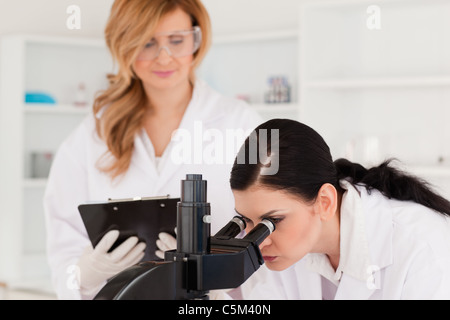 Dark-haired scientist and her assistant conducting an experiment Stock Photo