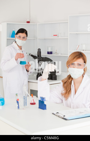 Blonde and dark-haired scientists posing in masks Stock Photo