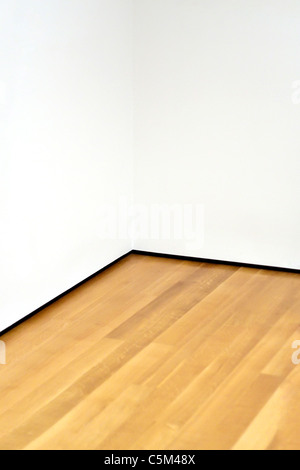 The corner of an empty room with wood floors and white walls. Lots of copy space. Stock Photo