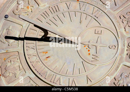 Sundial with Zodiac signs and figures surrounding Roman numeral times ...