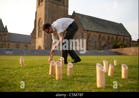 a man setting up a home-made version of the Finnish game "Molkky" Stock Photo