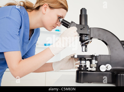 Female scientist conducting an experiment looking through a microscope Stock Photo