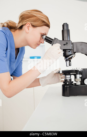 Blond-haired scientist looking through a microscope Stock Photo