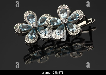 earrings of white gold with blue gems with reflecting on dark gray background Stock Photo