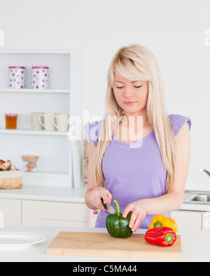 Attractive blonde woman cutting vegetables in modern kitchen interior Stock Photo