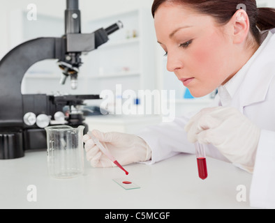 Cute red-haired female scientist doing an experiment in a lab Stock Photo