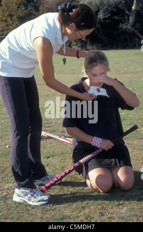 teacher with young girl having nosebleed in sports field Stock Photo