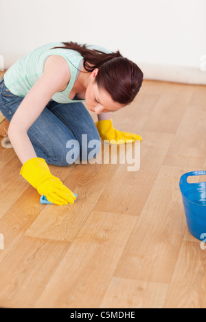 Pretty red-haired woman cleaning the floor while kneeling Stock Photo