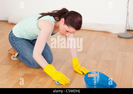 Gorgeous red-haired woman cleaning the floor while kneeling Stock Photo
