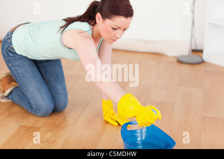 Cute red-haired woman cleaning the floor while kneeling Stock Photo