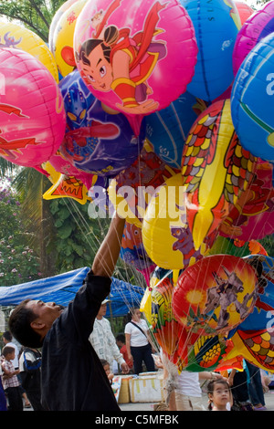 A balloon salesman is holding many colorful festival balloons at a Lao New Year festival in Luang Prabang, Laos. Stock Photo