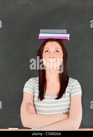 Portrait of a smilling cute woman balancing books on her head Stock Photo